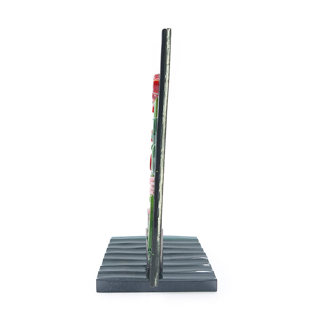 Side view of the Red Roses Panel, a fused glass art piece featuring red and orange flowers against a swirling green background, mounted on a dark green base.