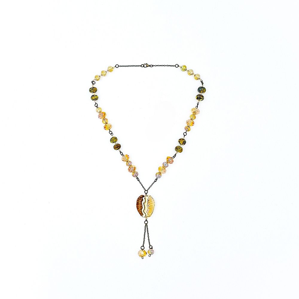 Wide view of a handmade amber lariat necklace featuring antique-bronze chain, patterned glass beads, faceted golden beads, a large amber and cream focal bead, and two dangling bead drops.
