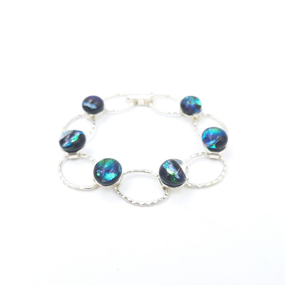 Silver-tone bracelet featuring iridescent blue-green oval glass beads alternating with open oval links, displayed on a white background.