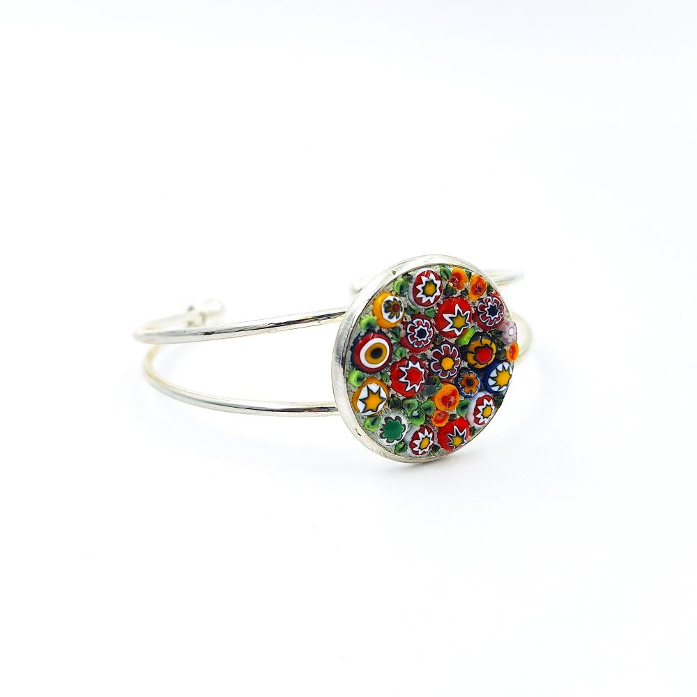 Silver-tone open cuff bracelet featuring a round mosaic glass face with red, white, yellow, orange, and green floral details on a white background.