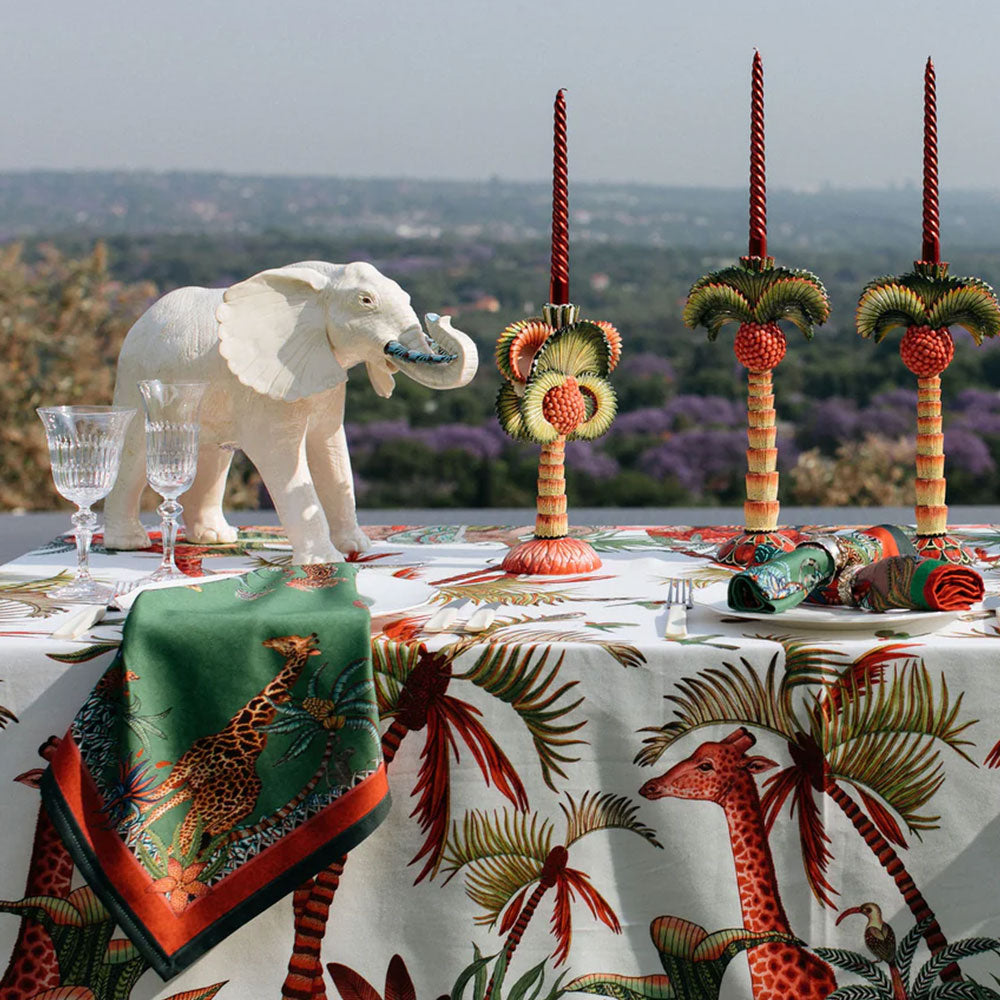 Sabie Forest Napkins styled on an outdoor dining table with coordinated wildlife and botanical linens, decorative candlesticks, glassware, and a white elephant sculpture.