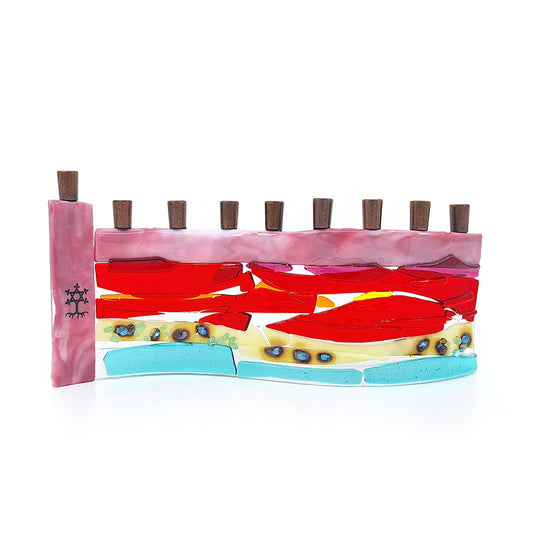 Handmade fused glass menorah featuring layered pink, red, orange, cream, and aqua glass with decorative blue accents and nine dark metal candle holders on a white background.
