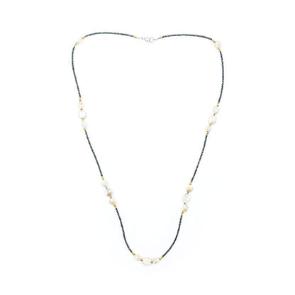Long necklace featuring tiny dark pyrite beads, peach moonstone oval beads, small gold-tone accents, and a silver-tone clasp, displayed on a white background.