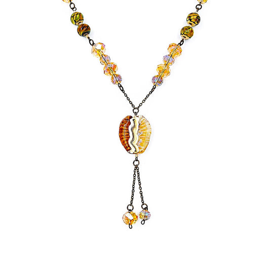 Close-up of a handmade amber lariat necklace showing faceted golden glass beads, patterned green and amber beads, an amber and cream focal bead, antique-bronze chain, and coordinating dangling bead drops.
