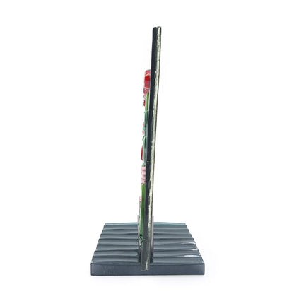 Side view of the Red Roses Panel, a fused glass art piece featuring red and orange flowers against a swirling green background, mounted on a dark green base. 