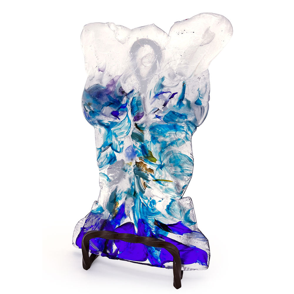 Angled view of a handmade translucent glass bust sculpture featuring flowing aqua, turquoise, cobalt blue, purple, and clear glass details, displayed on a dark metal stand against a white background.