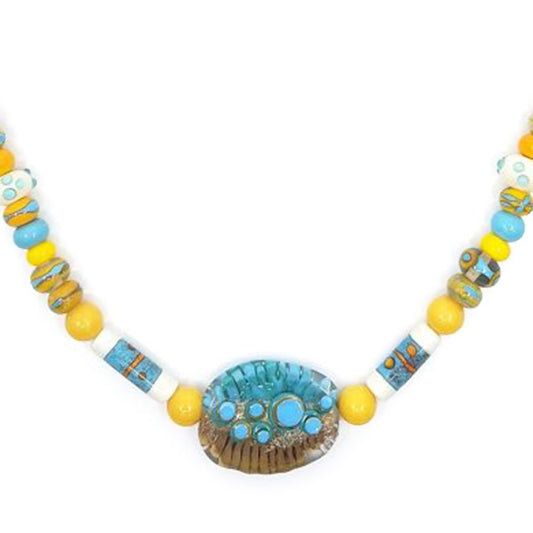 Close-up of a yellow and turquoise glass bead necklace featuring patterned accent beads and an oval turquoise and brown focal bead with raised circular details.