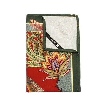 Folded Ardmore tea towel showing colorful tropical flowers, foliage, and part of a pangolin illustration with a dark green border.