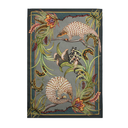 Rectangular Ardmore tea towel featuring three illustrated pangolins among tropical flowers, curling foliage, and a large patterned butterfly on a deep green background.