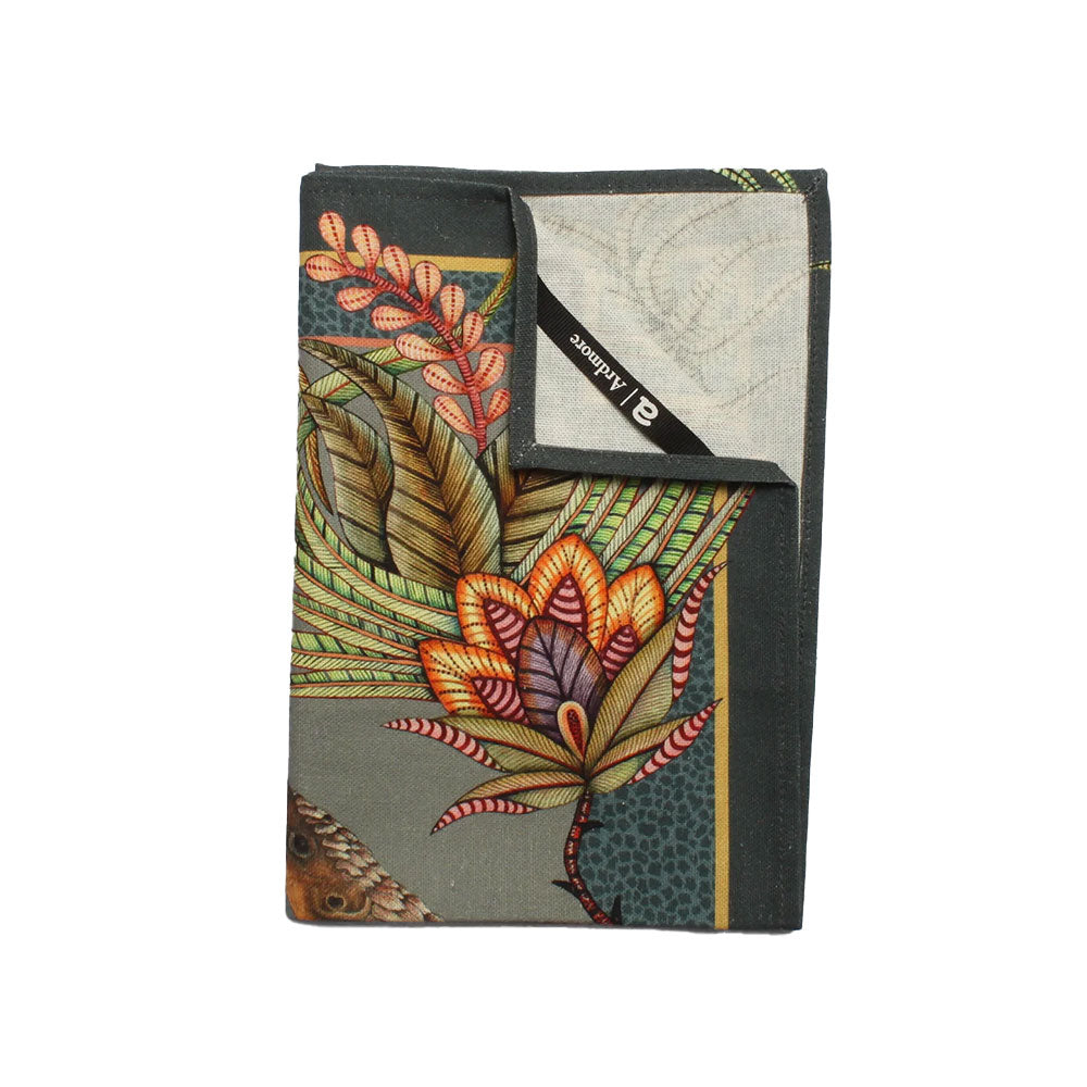 Folded Ardmore tea towel showing richly detailed tropical flowers, foliage, and a partial pangolin illustration with a dark green border.