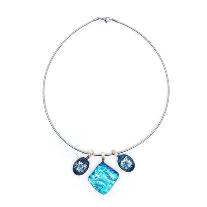 Full view of a stainless steel chain necklace featuring three blue dichroic glass charms with sterling silver pinch bails, including a square center pendant and two smaller oval side charms.