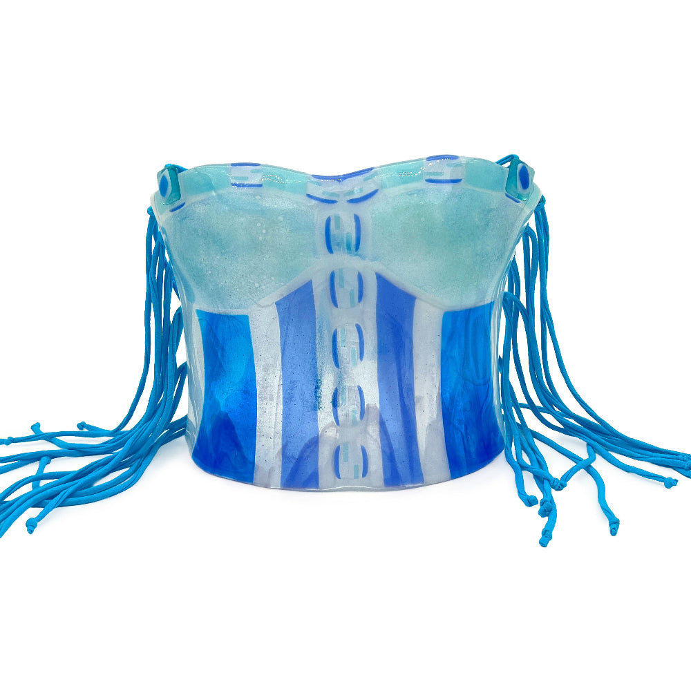 Front view of a handmade fused glass corset sculpture featuring layered aqua, turquoise, cobalt blue, and clear vertical glass panels with long bright blue cord fringe on both sides.