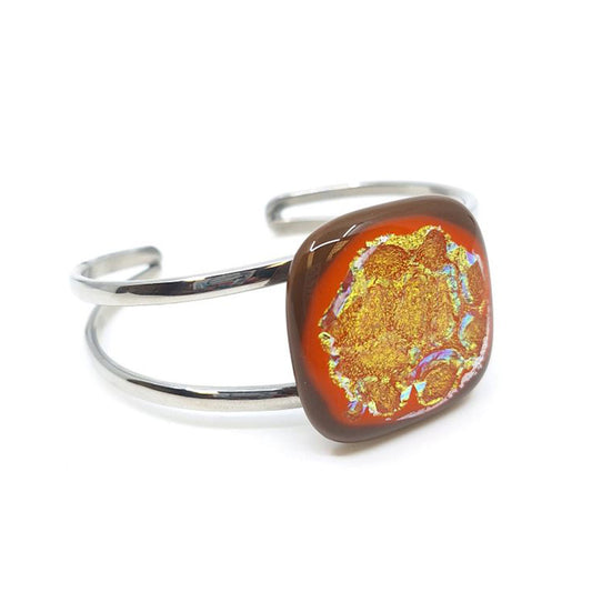 Citrus Supernova bangle bracelet with orange dichroic fused glass on a silver-tone metal band.