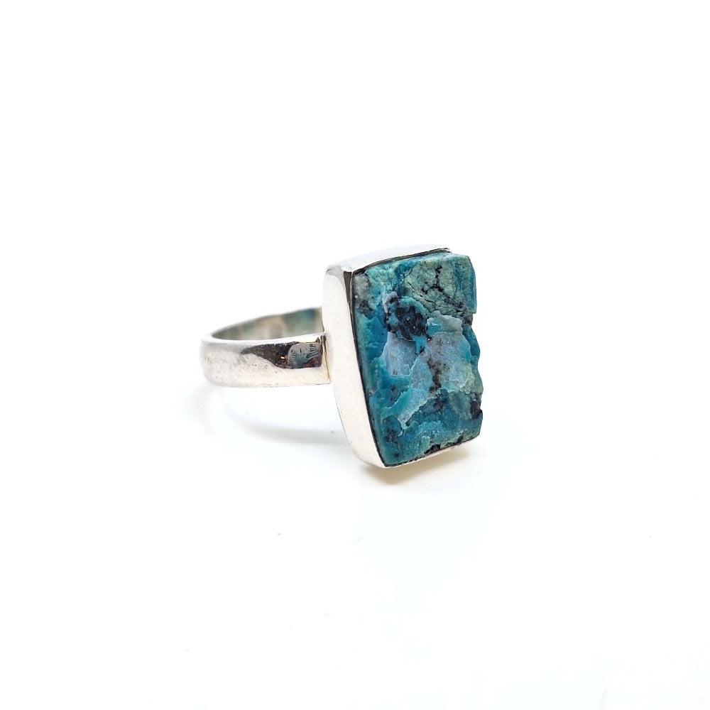Angled view of a chrysocolla ring with a rectangular teal stone centerpiece on a silver-toned band.