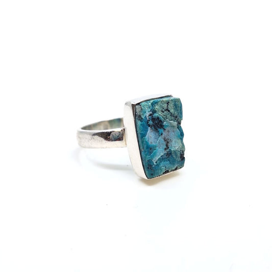 Angled view of a chrysocolla ring with a rectangular teal stone centerpiece on a silver-toned band.