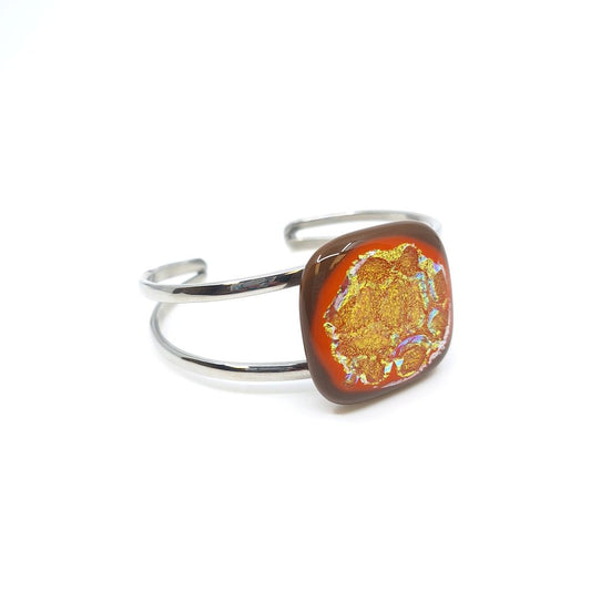 Citrus Supernova bangle bracelet with orange dichroic fused glass on a silver-tone metal band.