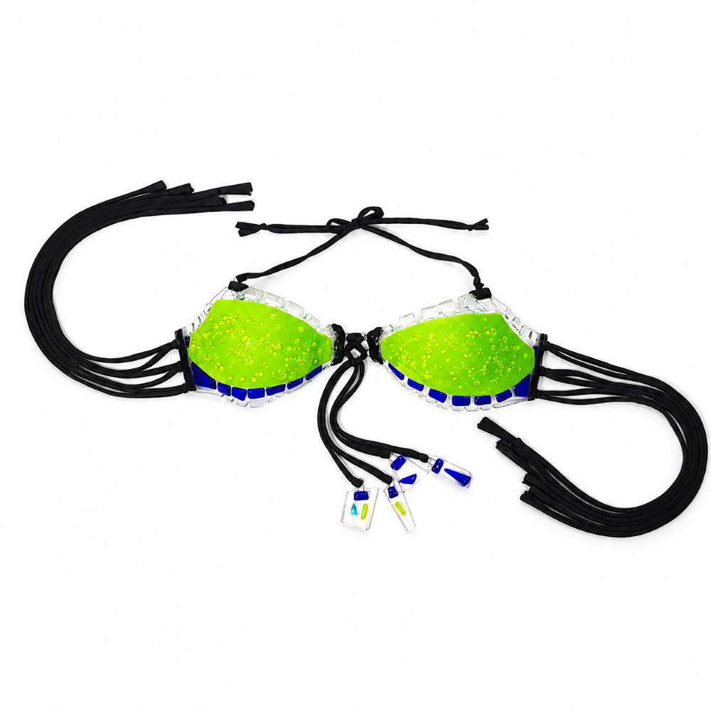 Full view of a handmade glass bikini top featuring vivid neon lime green glass cups, cobalt blue accents, clear glass edging, black ties, and decorative glass tassel details on a white background.