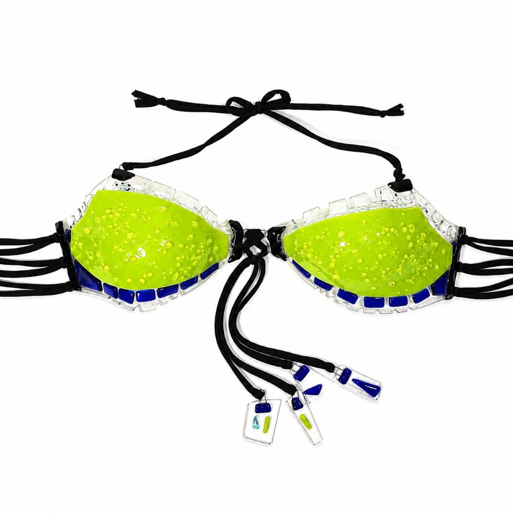 Handmade neon lime green glass bikini top featuring textured glass cups, cobalt blue and clear glass accents, black tie straps, and dangling glass charm details on a white background.