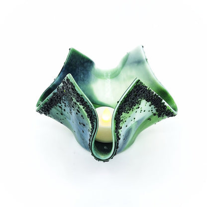 Handmade green and white glass tulip candle holder shown with a glowing candle inside, featuring sculpted asymmetrical petals and textured dark green accents.