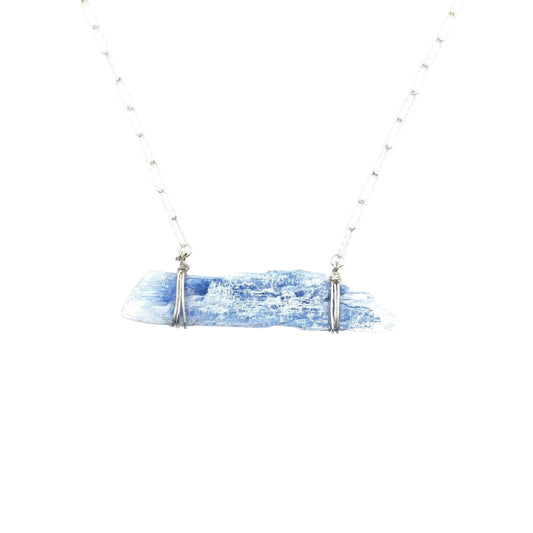 Close-up of a kyanite bar necklace featuring a natural pale blue kyanite crystal suspended horizontally from a delicate silver-tone chain with simple wire accents.