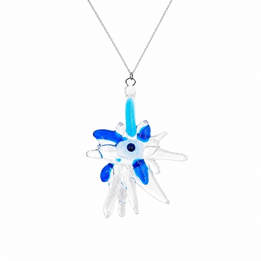 Close-up of a handmade glass pendant necklace featuring an abstract starburst design in clear, aqua, and cobalt blue glass with a small dark blue center accent.