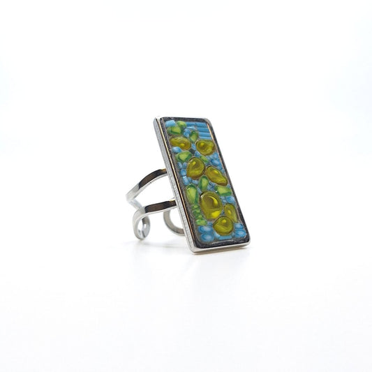 Ring with a rectangular mosaic face in green, blue, and yellow on a silver-toned band.