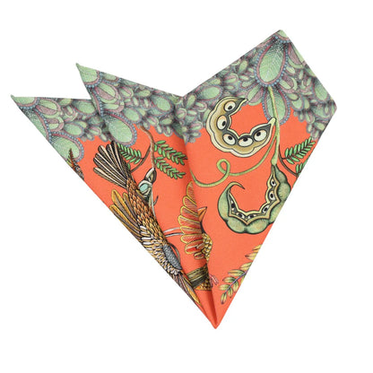 Folded coral Thanda Nest napkins showing African masked weaver birds, seed pods, foliage, and patterned edging.