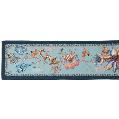 Full-length mist blue Thanda Nest table runner with birds, flowers, foliage, and woven nest details.
