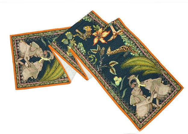 Folded Ardmore table runner featuring a leopard, elephants, birds, tropical flowers, and lush foliage on a deep green background with an orange border.