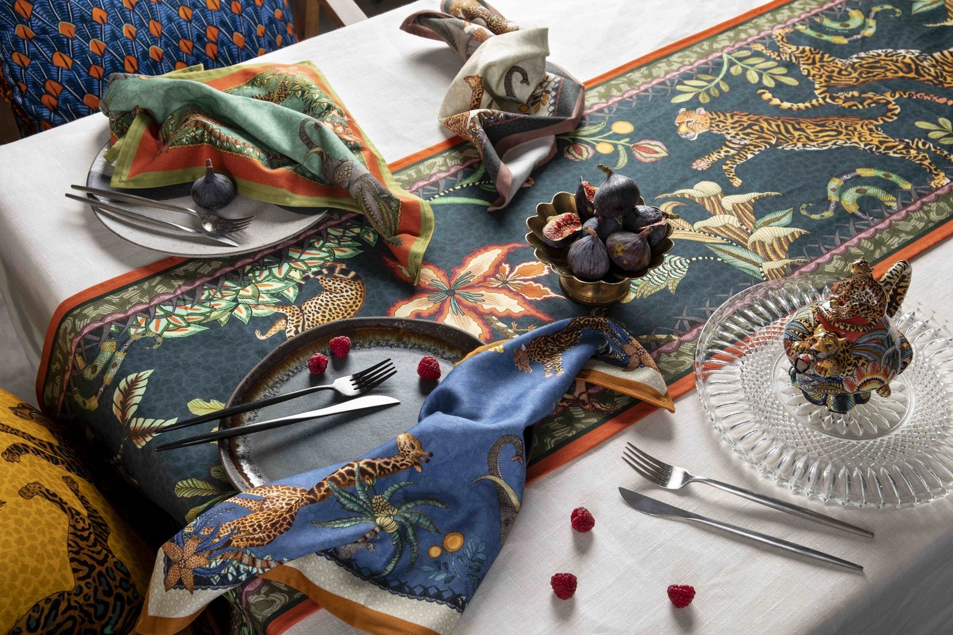 Ardmore wildlife table runner styled on a dining table with coordinating napkins, glassware, fruit, and animal-themed table accessories.