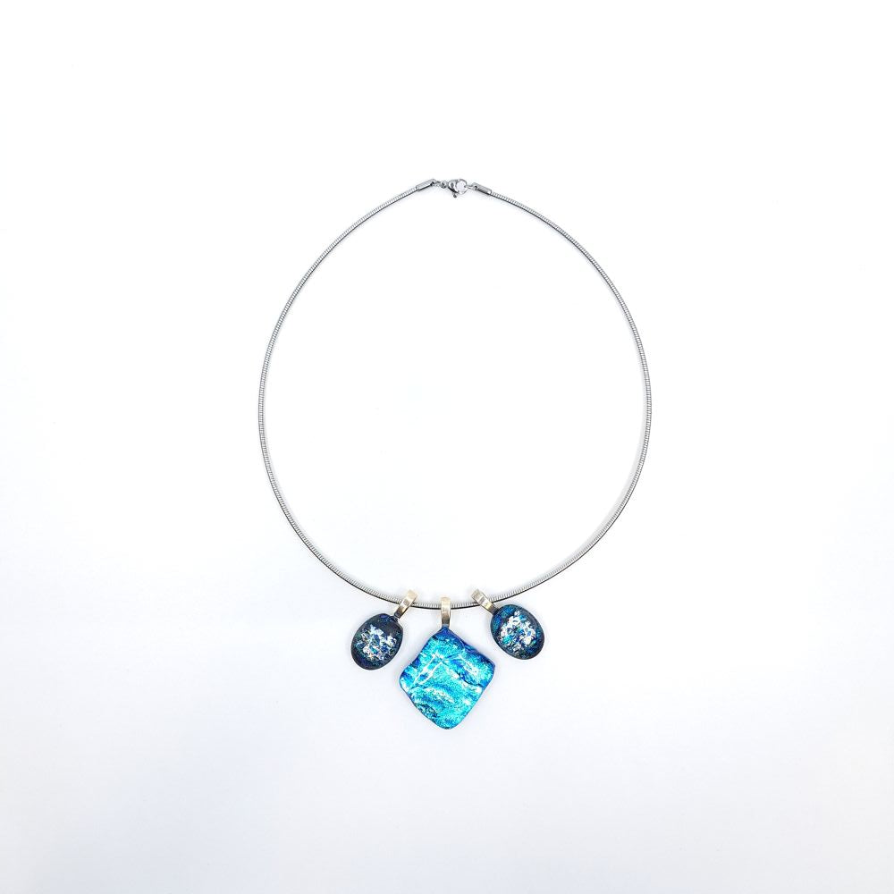 Full view of a stainless steel chain necklace featuring three blue dichroic glass charms with sterling silver pinch bails, including a square center pendant and two smaller oval side charms.