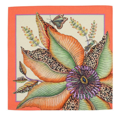 Thanda Bloom napkin with a large orange and green flower, butterfly, foliage, and coral border.