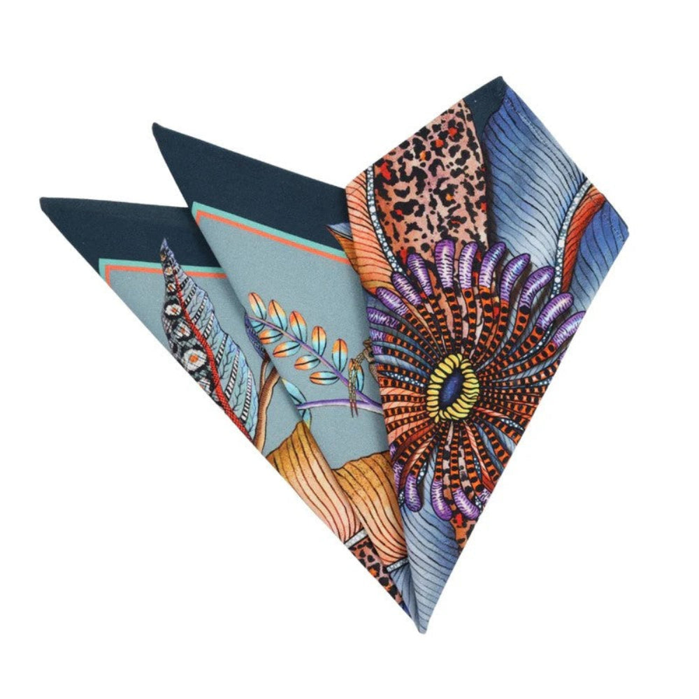 Folded Thanda Bloom napkins in mist blue showing floral, butterfly, foliage, and patterned details.