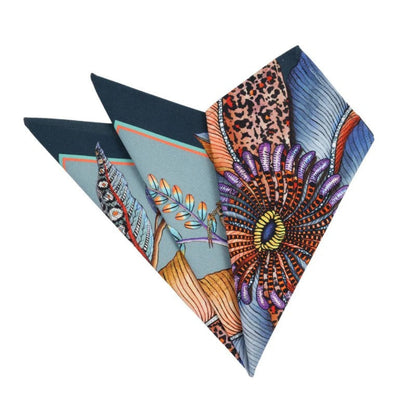 Folded Thanda Bloom napkins in mist blue showing floral, butterfly, foliage, and patterned details.