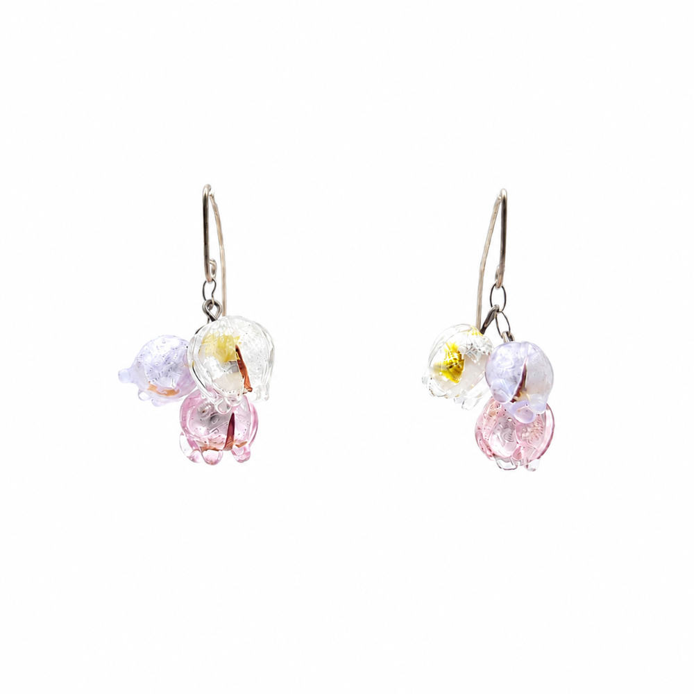 Pair of floating silver-tone drop earrings featuring clusters of translucent glass flowers in clear, pale lavender, and soft pink on a white background.