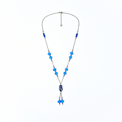 Wide view of a handmade blue lariat necklace featuring antique-bronze chain, bright blue glass beads, a decorative deep blue focal bead, and two dangling bead drops.