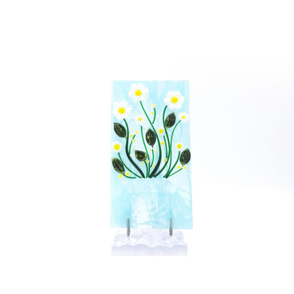 Front view of the White Daisies Panel featuring white flowers with yellow centers, green stems, and dark green leaves on a pale blue glass background with a white textured base.