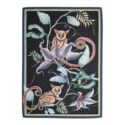 Bush Baby Tea Towel featuring two illustrated bush babies surrounded by curling vines, seed pods, flowers, and layered foliage on a deep black background with a subtle border. 
