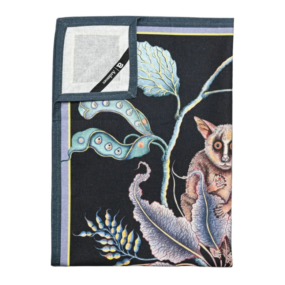 Back and folded view of the Bush Baby Tea Towel showing the patterned front, light fabric backing, dark border, and Ardmore label. 