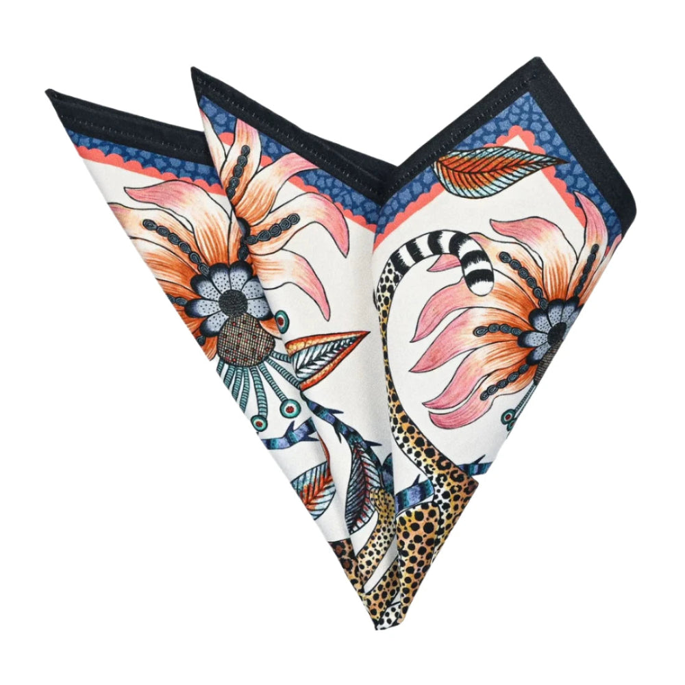 Leopard-and-floral cloth napkin folded into a decorative pointed shape, showing coral flowers, patterned foliage, and a navy border.