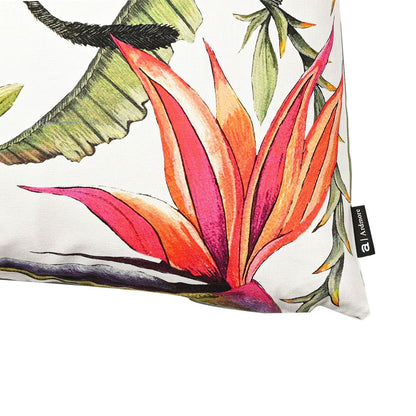 Close-up detail of the white Monkey Bean Pillow showcasing a vibrant pink bird of paradise flower and the brand tag along the edge. 