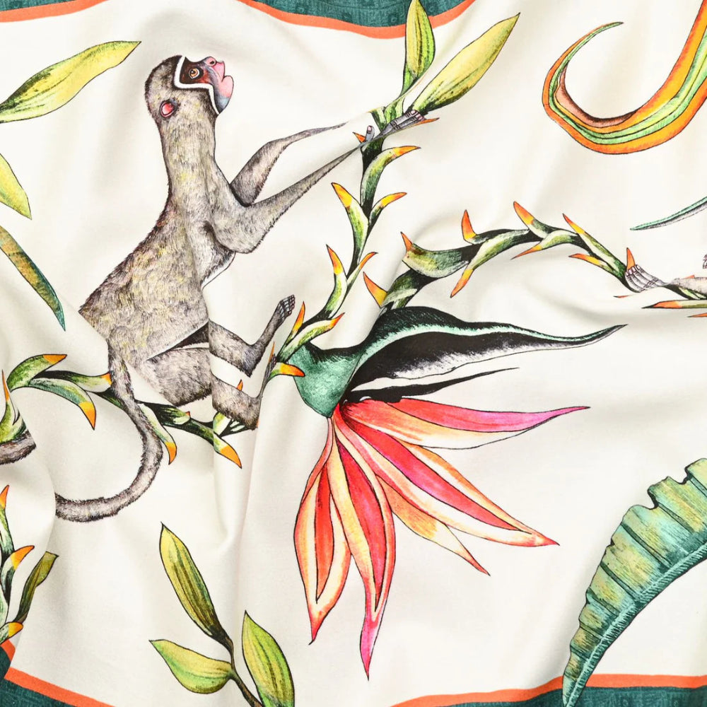 Close-up of the Monkey Paradise Table Runner Large showing an illustrated monkey perched among colorful tropical leaves and a bird of paradise flower on a cream background