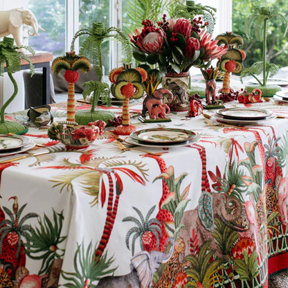 Palm Parade tablecloth styled on a dining table with tropical foliage, animal figures, and colorful table settings.