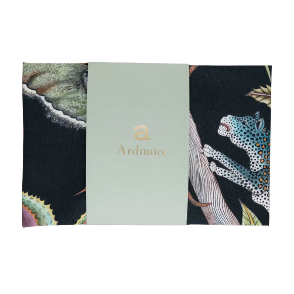 Folded Pangolin Park Tea Towel by Ardmore wrapped with a light green branded paper band, showing sections of the black wildlife and botanical print.