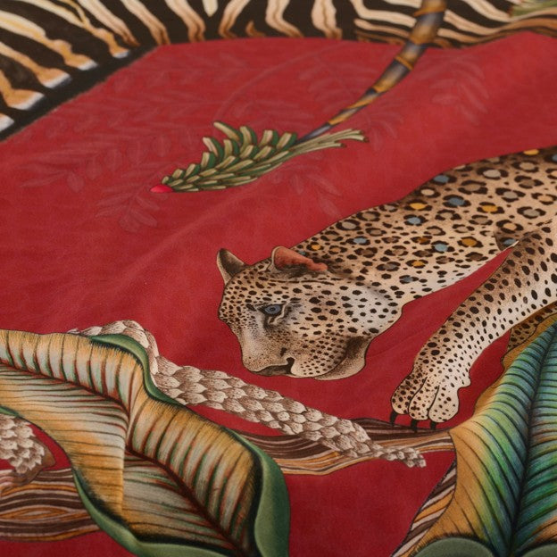 Close-up of the Ardmore tablecloth showing a detailed leopard among oversized tropical leaves against the red patterned background.