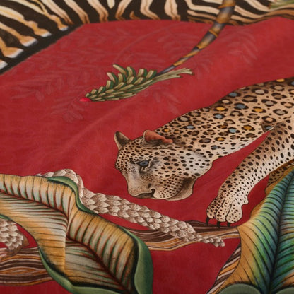 Close-up of the Ardmore tablecloth showing a detailed leopard among oversized tropical leaves against the red patterned background.
