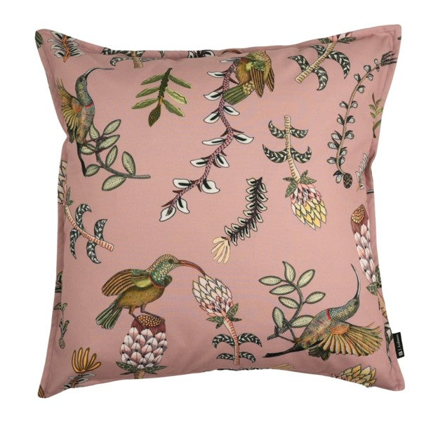 Square blush pink decorative pillow featuring colorful hummingbirds, flowering plants, leafy branches, and scattered botanical illustrations.