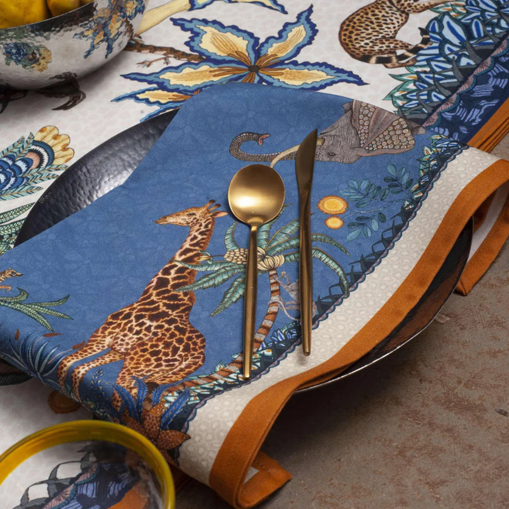 Sabie Forest napkin styled on a table with gold flatware, giraffe, elephant, and botanical details.