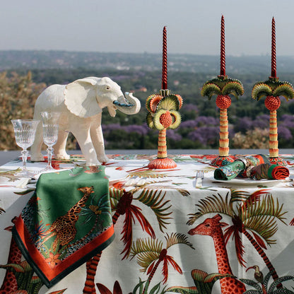 Sabie Forest Napkins styled on an outdoor dining table with coordinated wildlife and botanical linens, decorative candlesticks, glassware, and a white elephant sculpture.