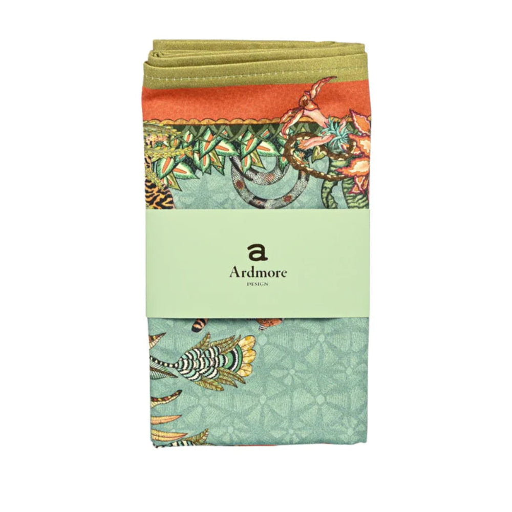 Folded Sabie Forest Napkin by Ardmore wrapped with a light green branded paper band, showing sections of the aqua wildlife print with coral and olive green border details.
